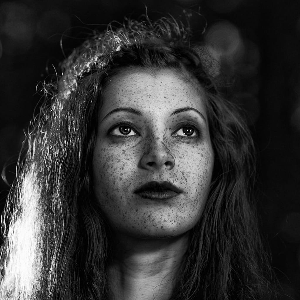 Jak przygotować się do portretowej sesji zdjęciowej w studiu i w plenerze? Kompleksowy przewodnik od fotografa 7 Czarno biały portret kobiety z piegami i artystycznym światłem, fotografia fine art beauty, klimatyczna sesja portretowa z mocnym kontrastem