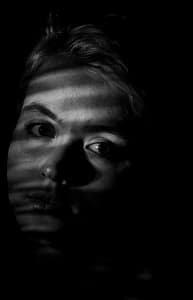 Kreatywny portret światłem – fotografia portretowa Lublin studio zbliżenie twarzy kobiety z cieniem światła, portret artystyczny czarno-biały