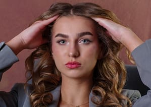 Portret kobiecy glamour z lokami, fotografia beauty na ciepłym tle, sesja zdjęciowa studio