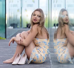 Fotografia fashion Lublin – sesja kobieca nowoczesna kobieta siedząca przy szklanej ścianie, fotografia fashion plenerowa