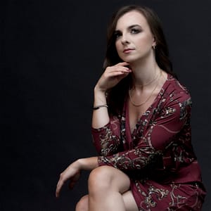 Elegancki portret kobiety w bordowej sukience na ciemnym tle, fotografia studyjna glamour beauty, klasyczna stylizacja i miękkie światło
