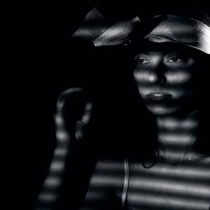 Noir shadow portrait Czarno-biały portret kobiety w kapeluszu z dramatycznym światłem przez żaluzje, fotografia artystyczna high contrast, minimalistyczna kompozycja i klimatyczny efekt noir
